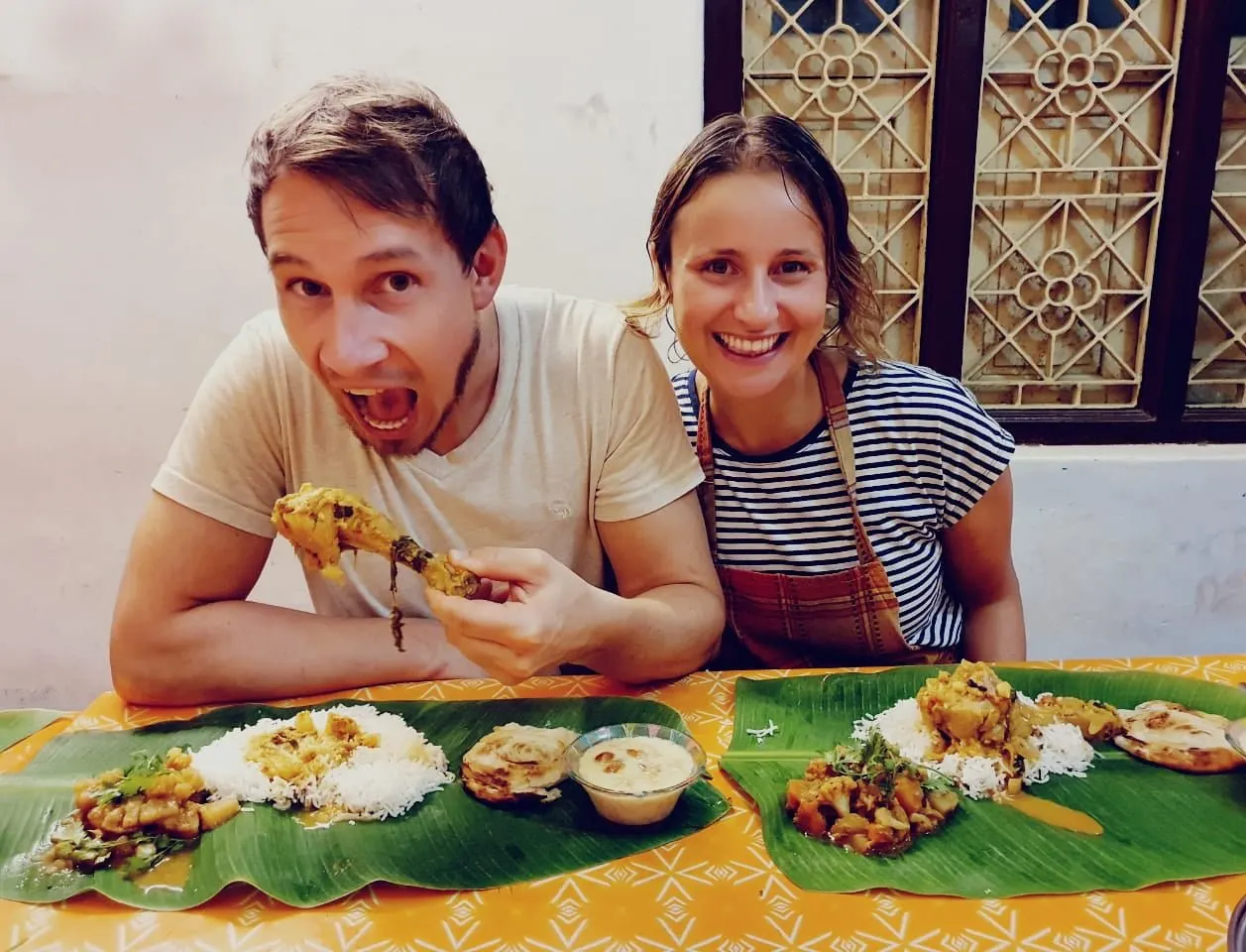 Two guests enjoy a South Indian meal on banana leaves after their cooking class